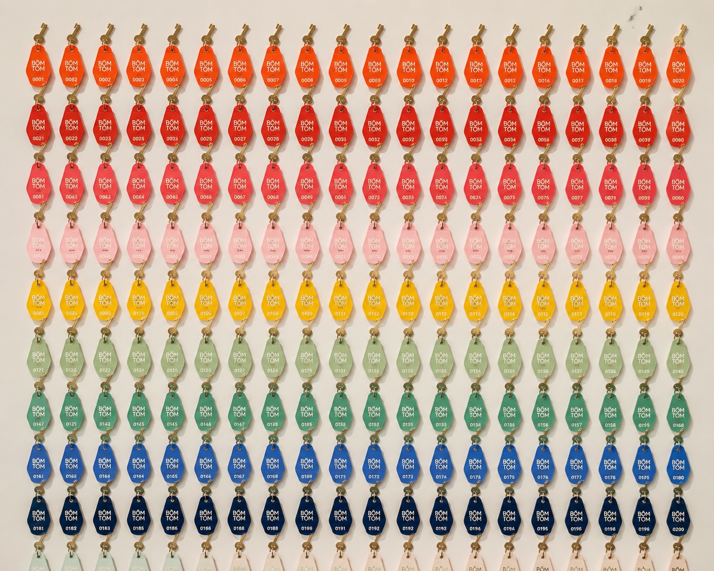 A wall of coloured room keys behind reception, ordered by colour